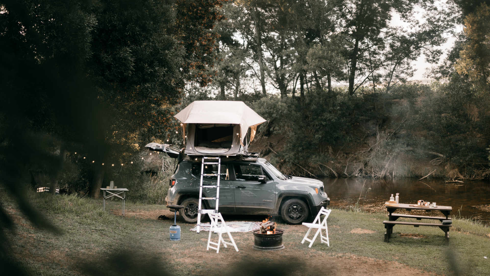 Van avec tente de toit au bord d’une rivière